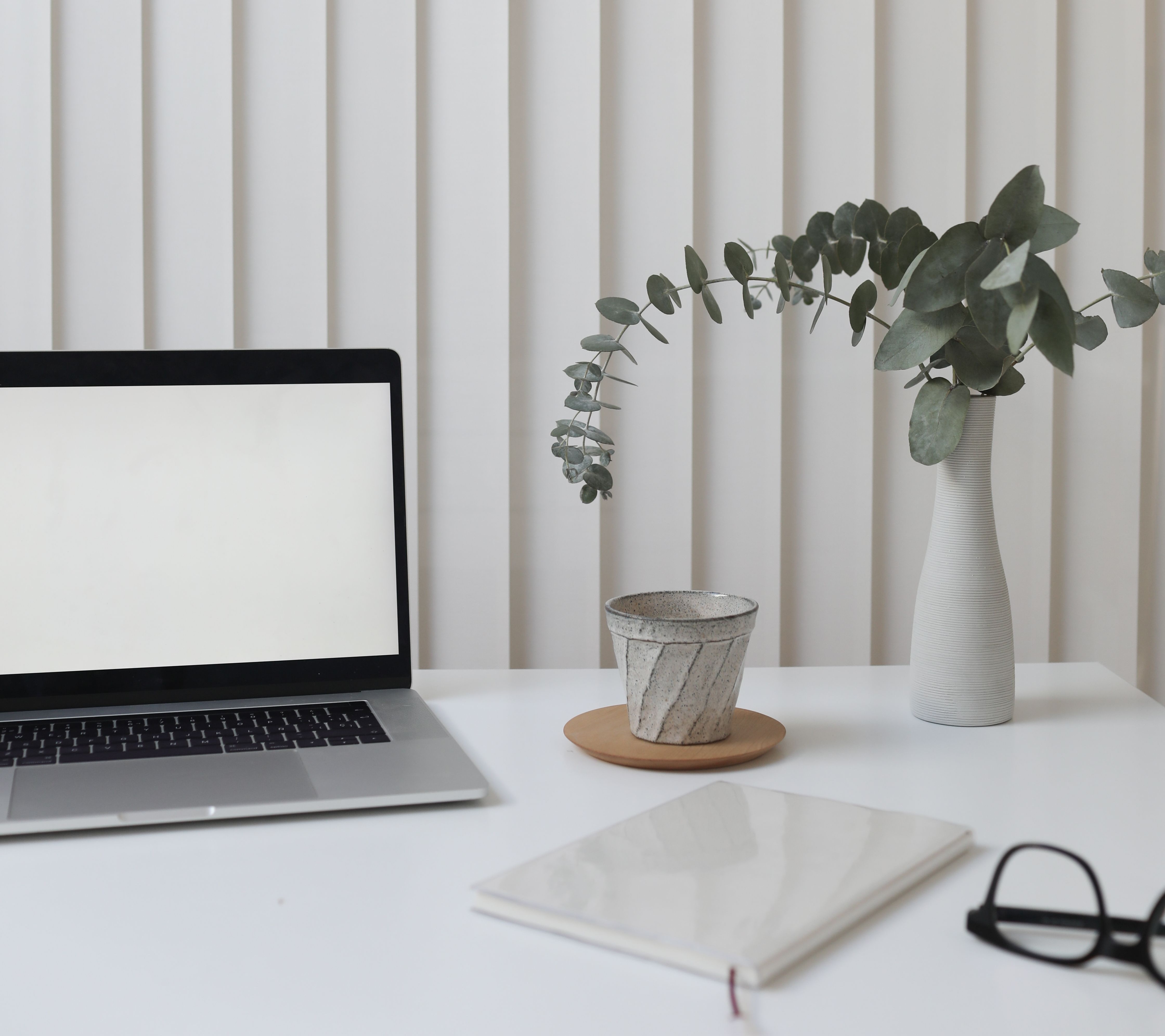 A working desk with a laptop, notebook, and morning light